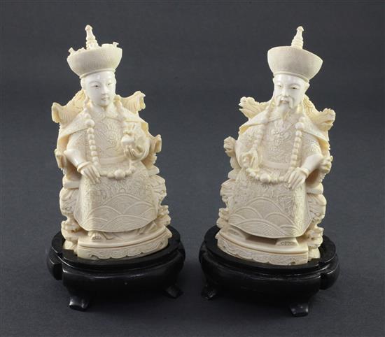 A pair of Chinese ivory seated figures of an emperor and empress, first half 20th century, 13.5cm excl. the wood stands